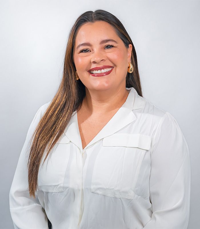 A woman wearing a black jacket and a necklace is smiling for the camera.