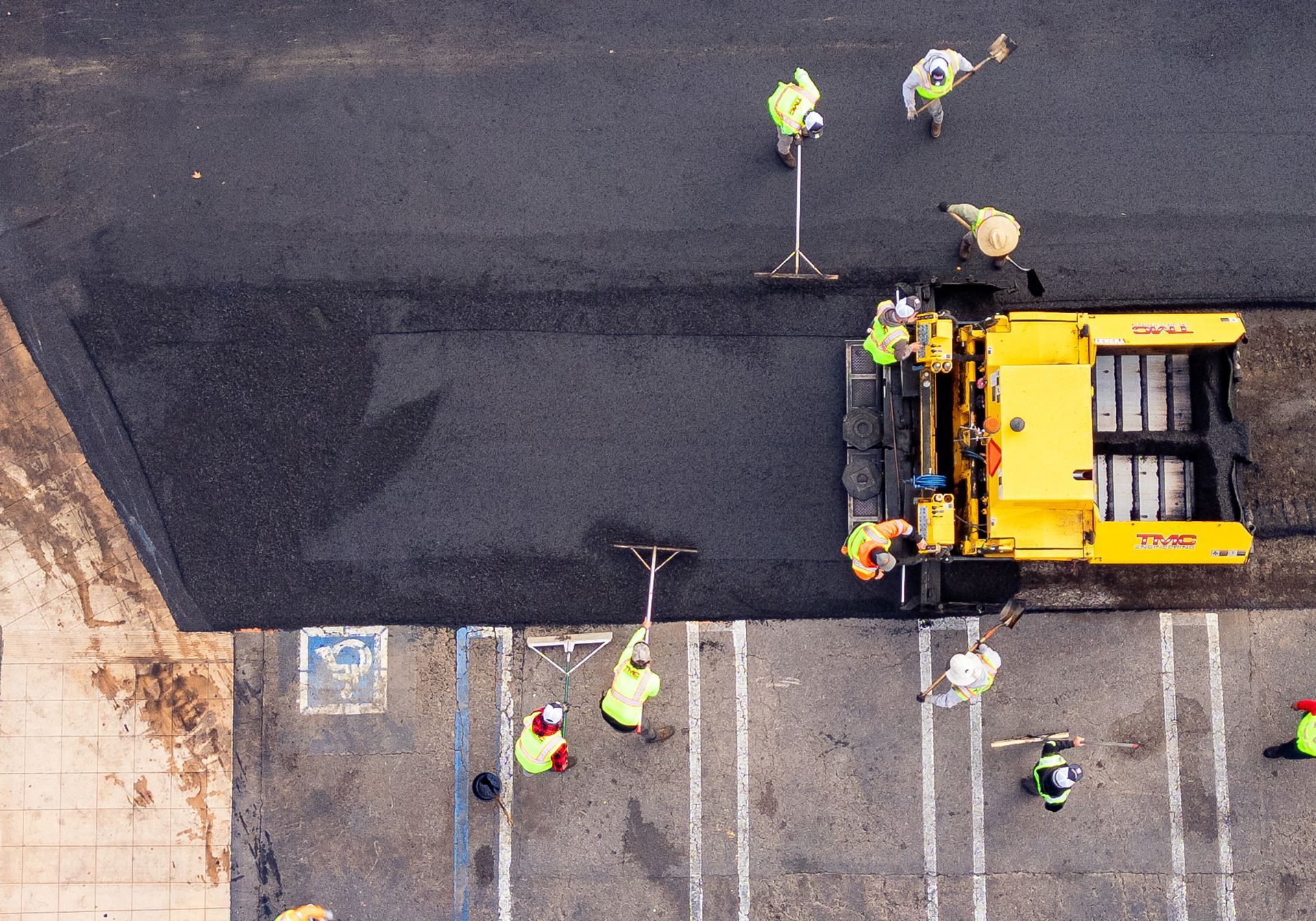 A group of construction workers are paving a parking lot.