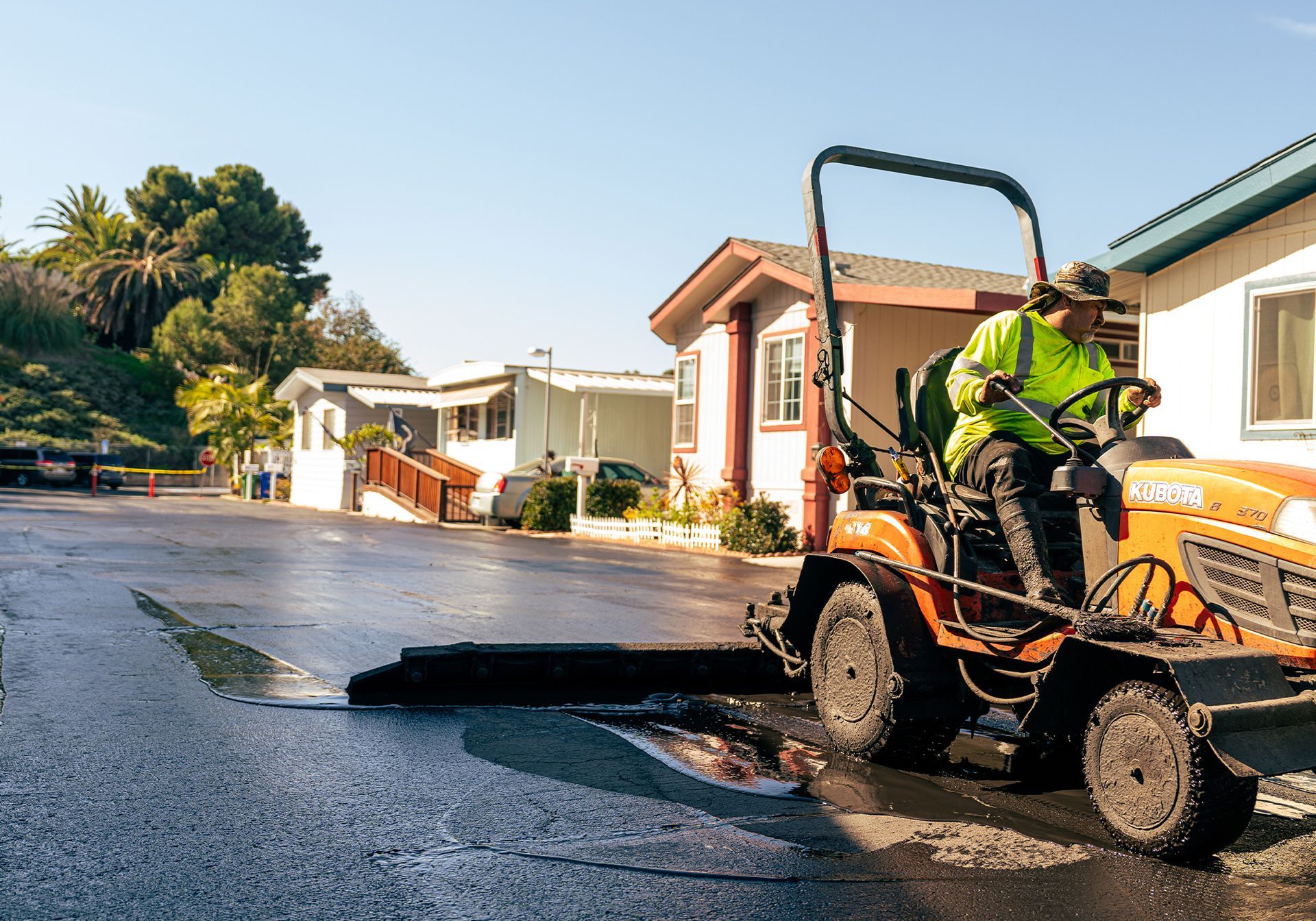 A man seal coating in a parking lot.
