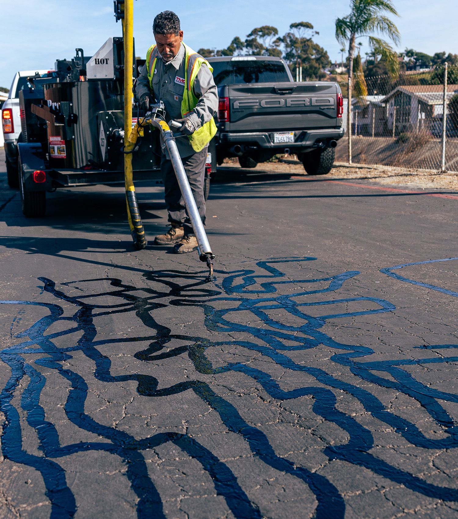 A man is working on a road with a ford truck in the background