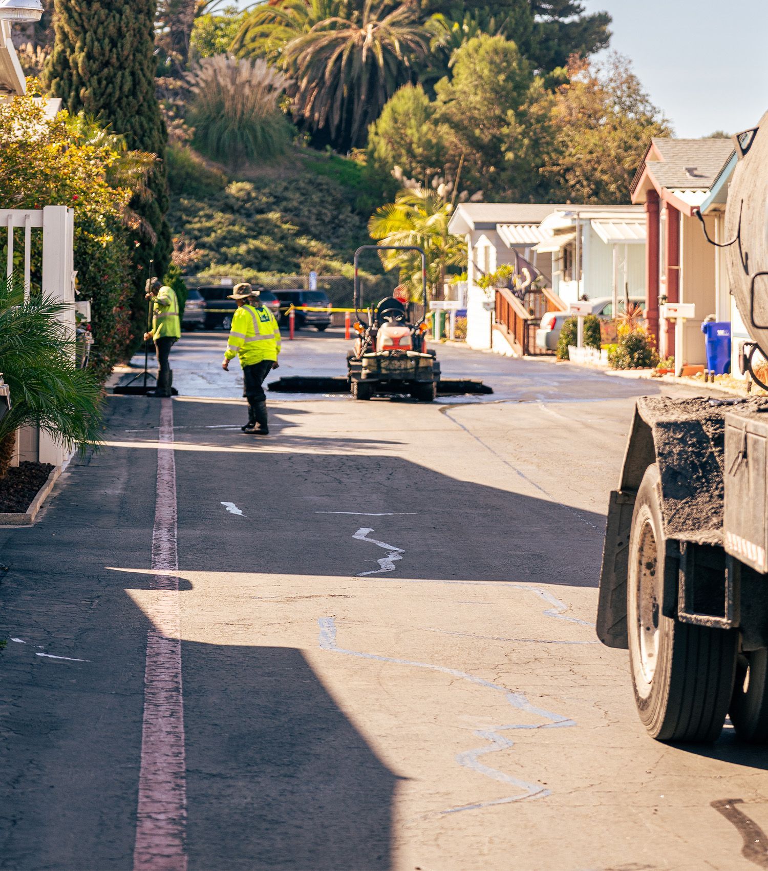A man in a yellow vest is walking down a street next to a truck