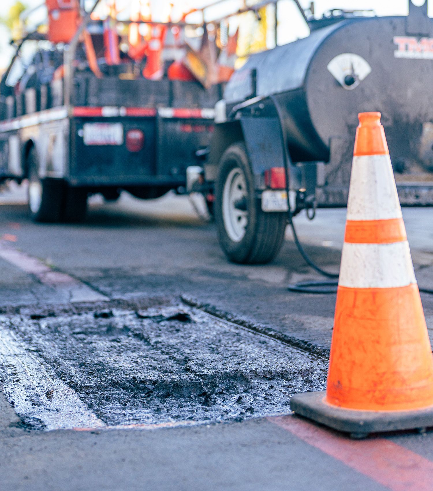 An orange and white traffic cone is in front of a truck