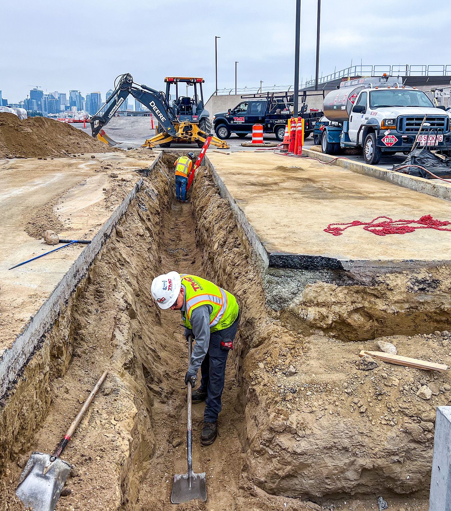 A construction worker is digging a trench with a shovel.