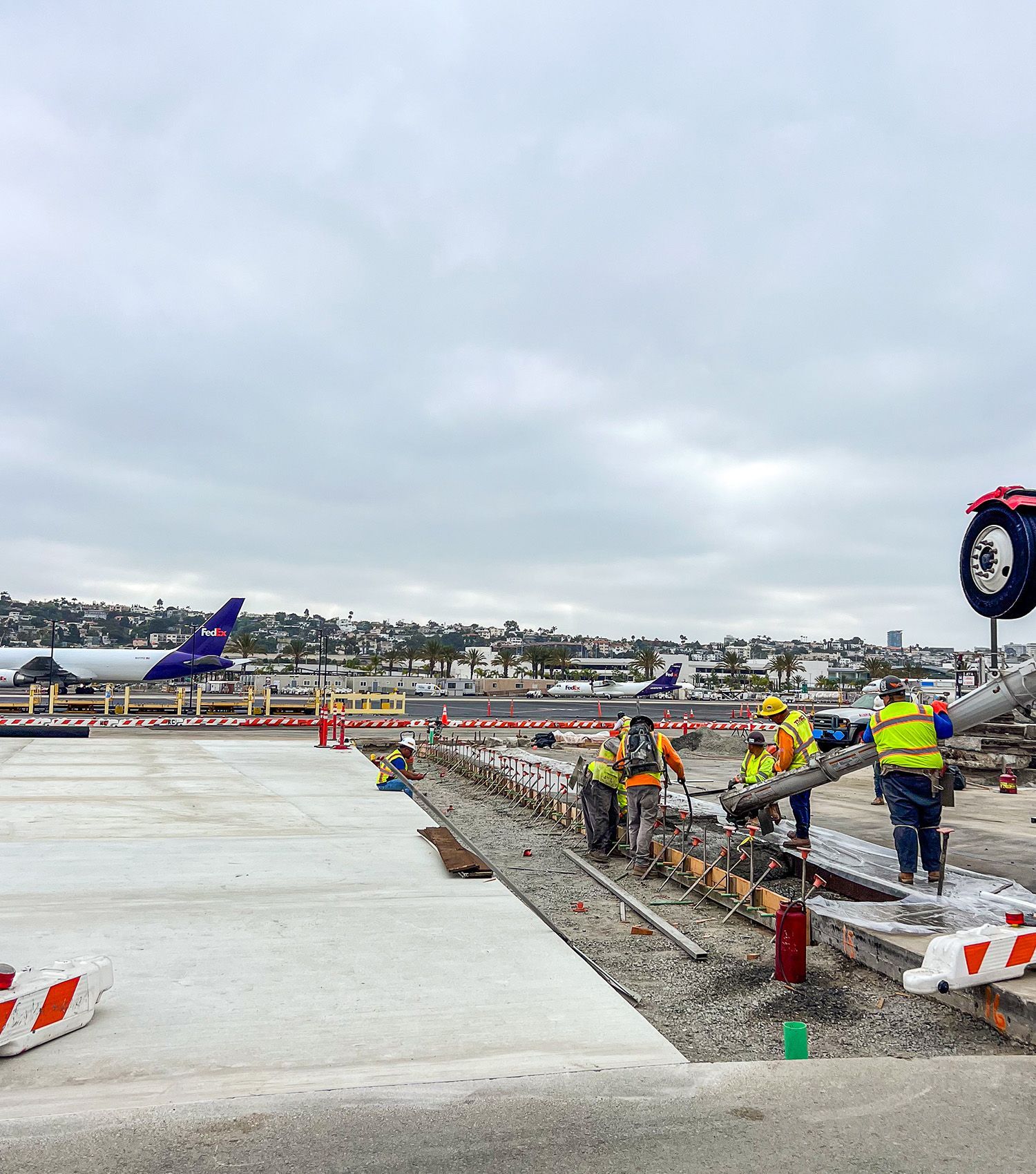 A group of construction workers are working on a runway at an airport.