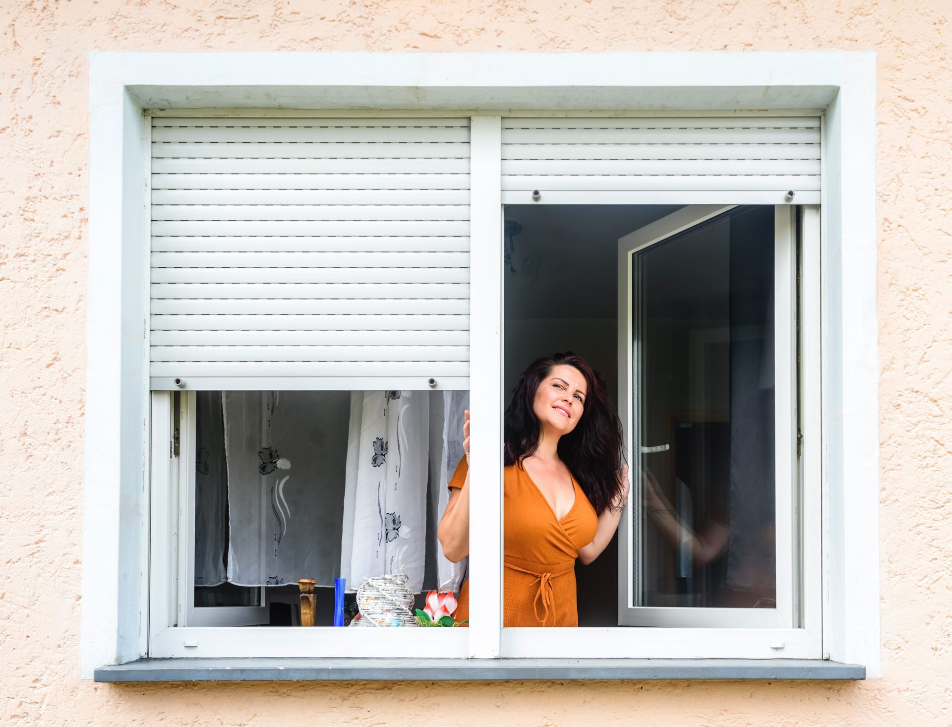 An outside view of a young woman opens a double-glazed window with blinds An outside view of a young woman opens a double-glazed window with blinds