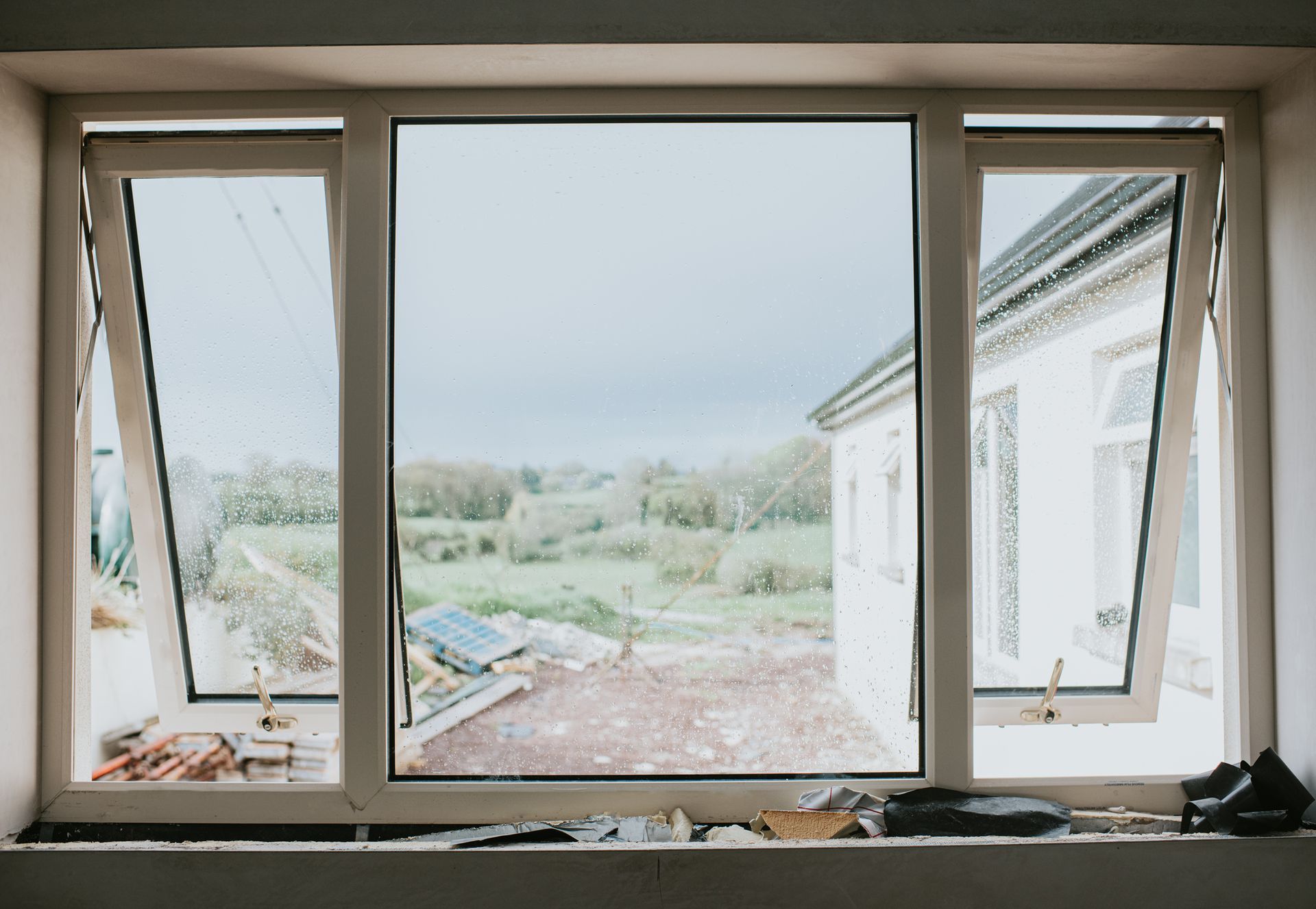 A large window with white frames with two side windows opened.