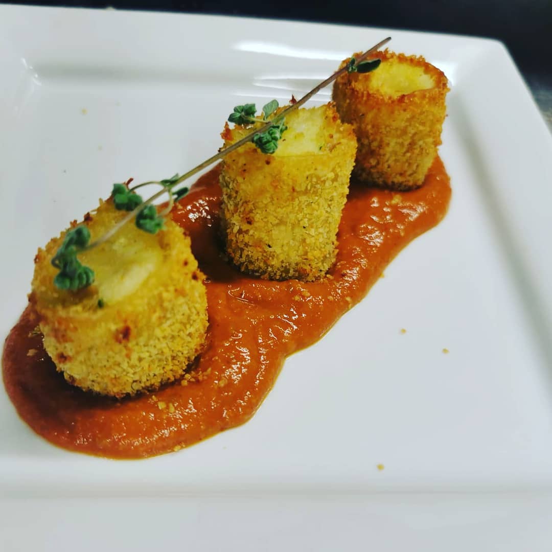Un piatto bianco condito con cibo fritto e salsa