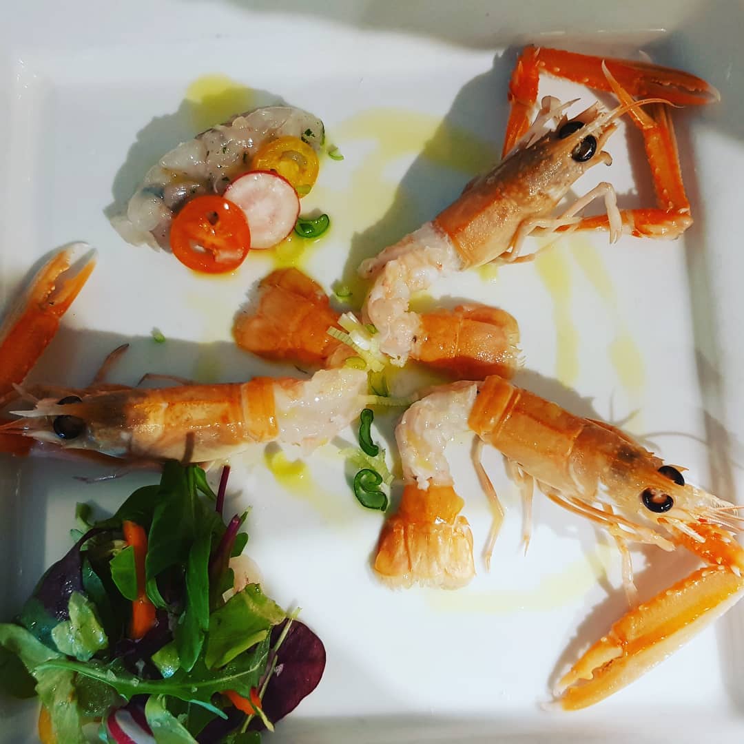 Un piatto bianco condito con gamberi e verdure