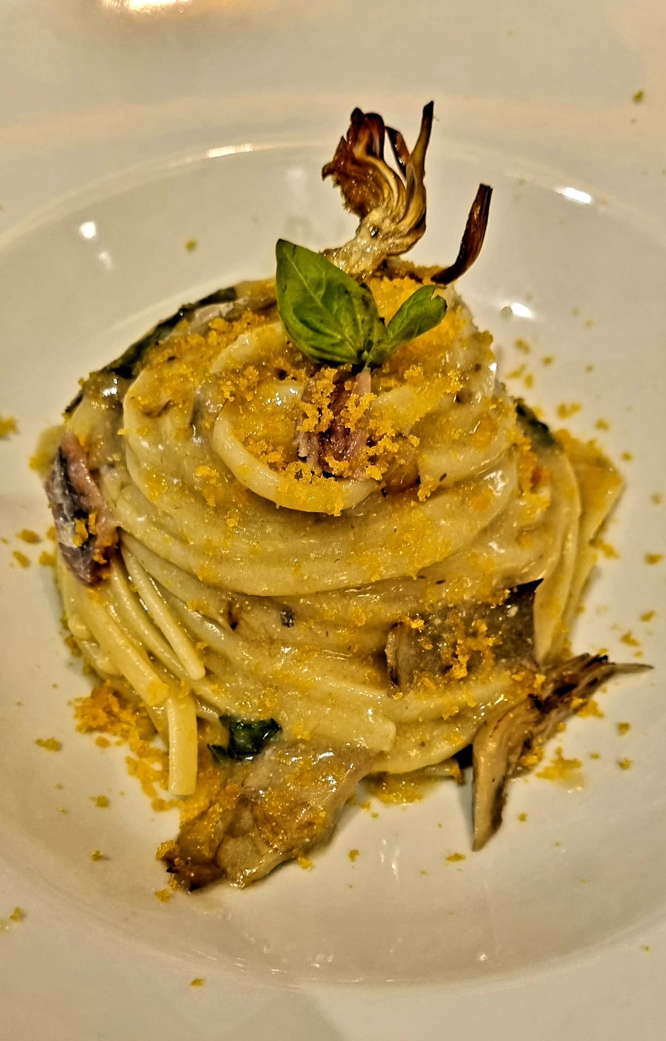 Un piatto bianco sormontato da una pila di pasta e verdure.