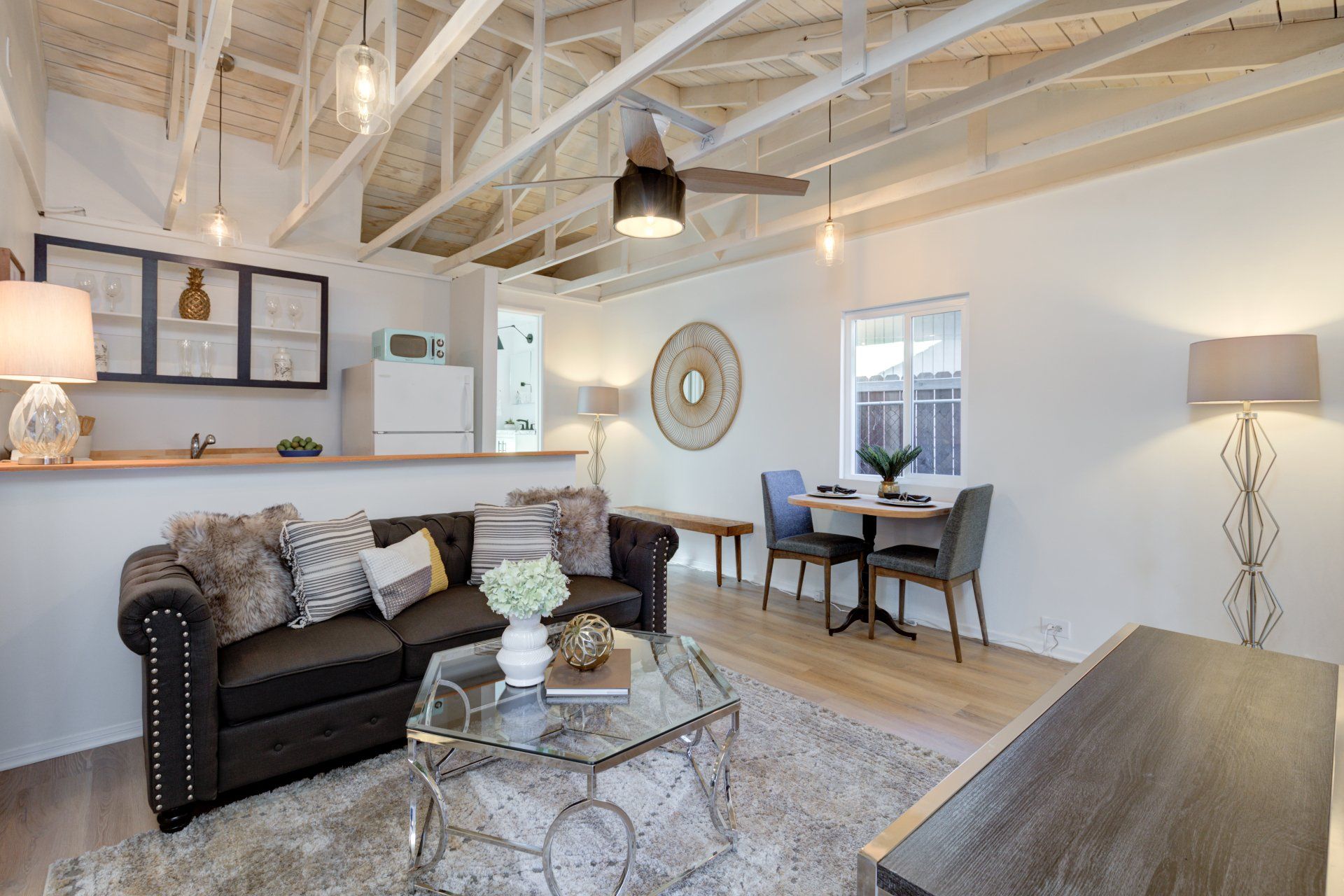 A living room with a couch , table , chairs and a ceiling fan.