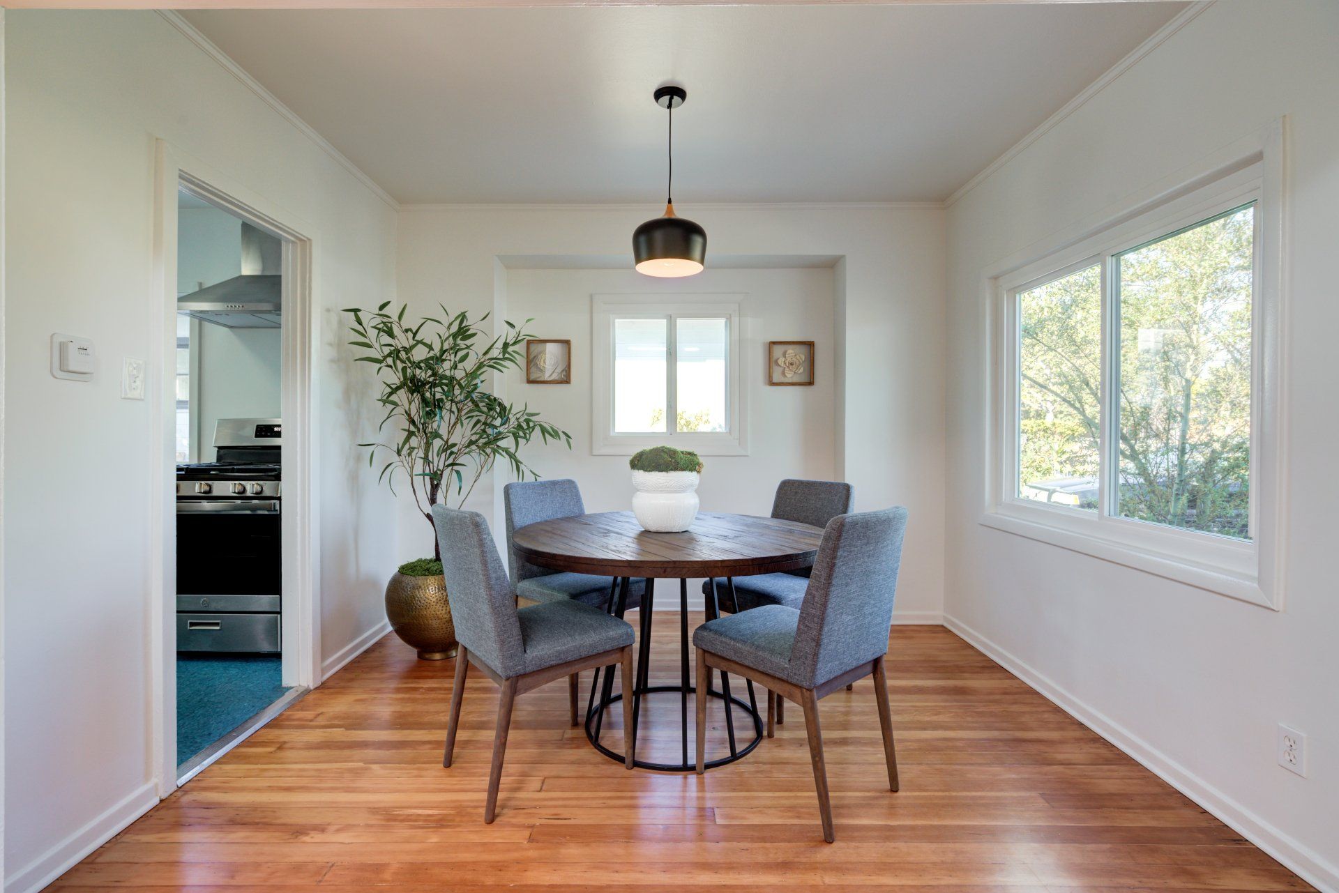A dining room with a table and chairs and a potted plant.