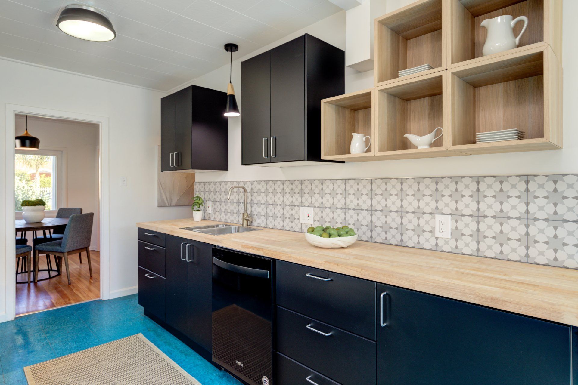 A kitchen with black cabinets and wooden counter tops.