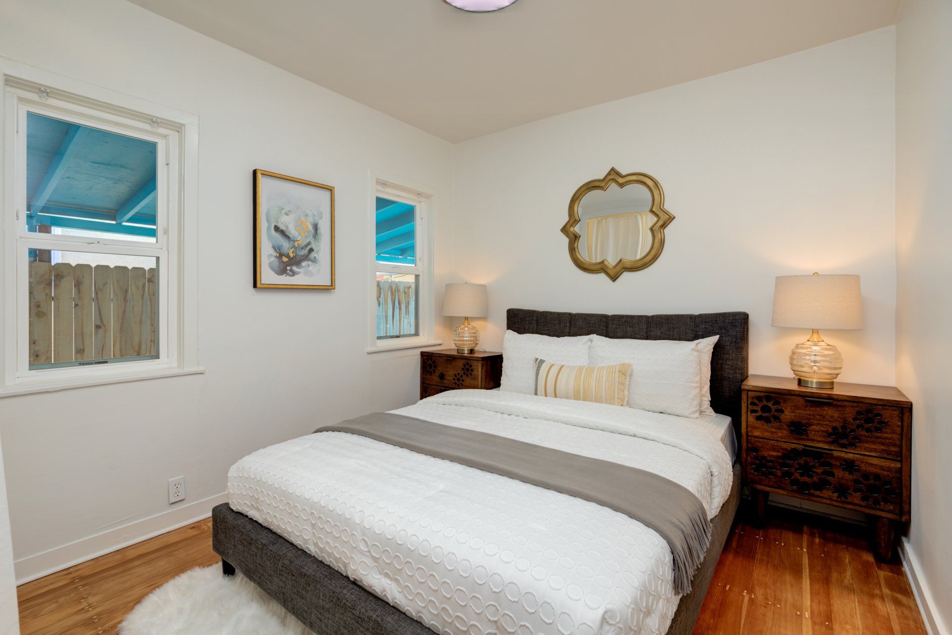 A bedroom with a bed , nightstands , lamps and a mirror.