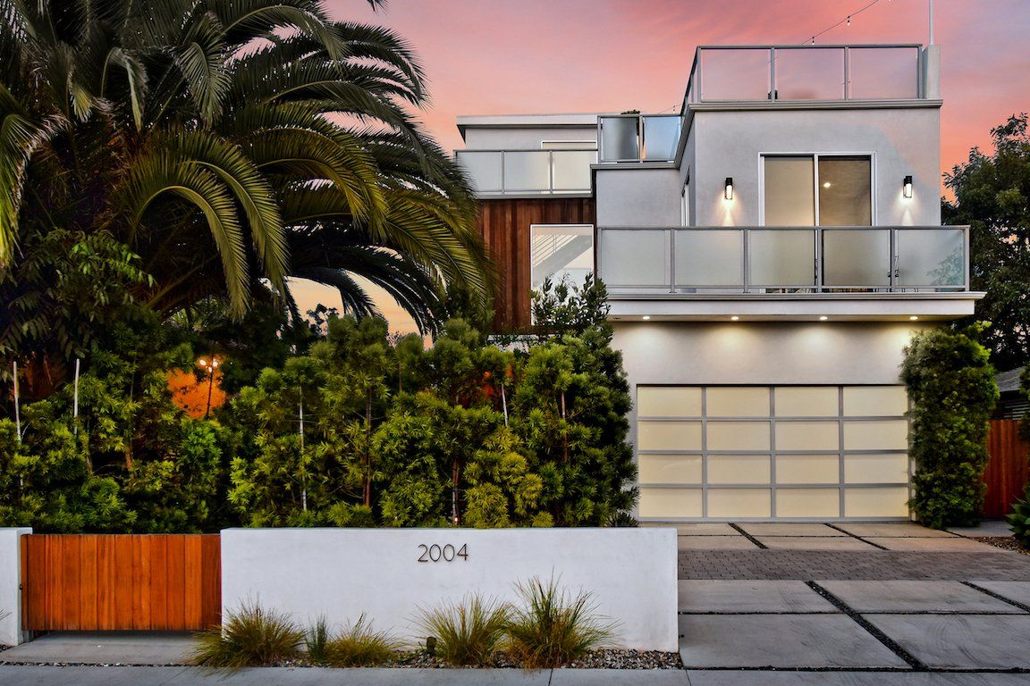 A modern house with a balcony and palm trees in front of it