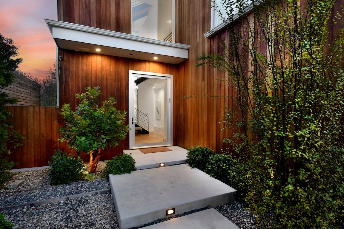 A wooden house with a concrete walkway leading to the door