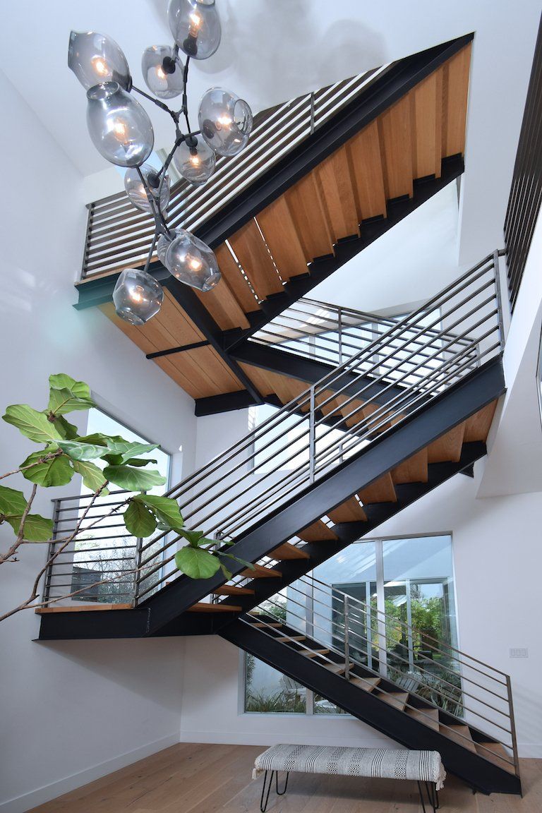 A staircase in a house with a chandelier hanging from the ceiling