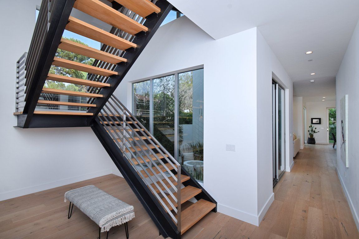 A wooden staircase with a metal railing in a hallway