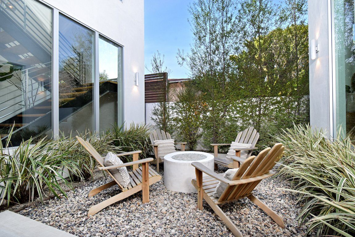 A patio with chairs and a fire pit in the middle of it.