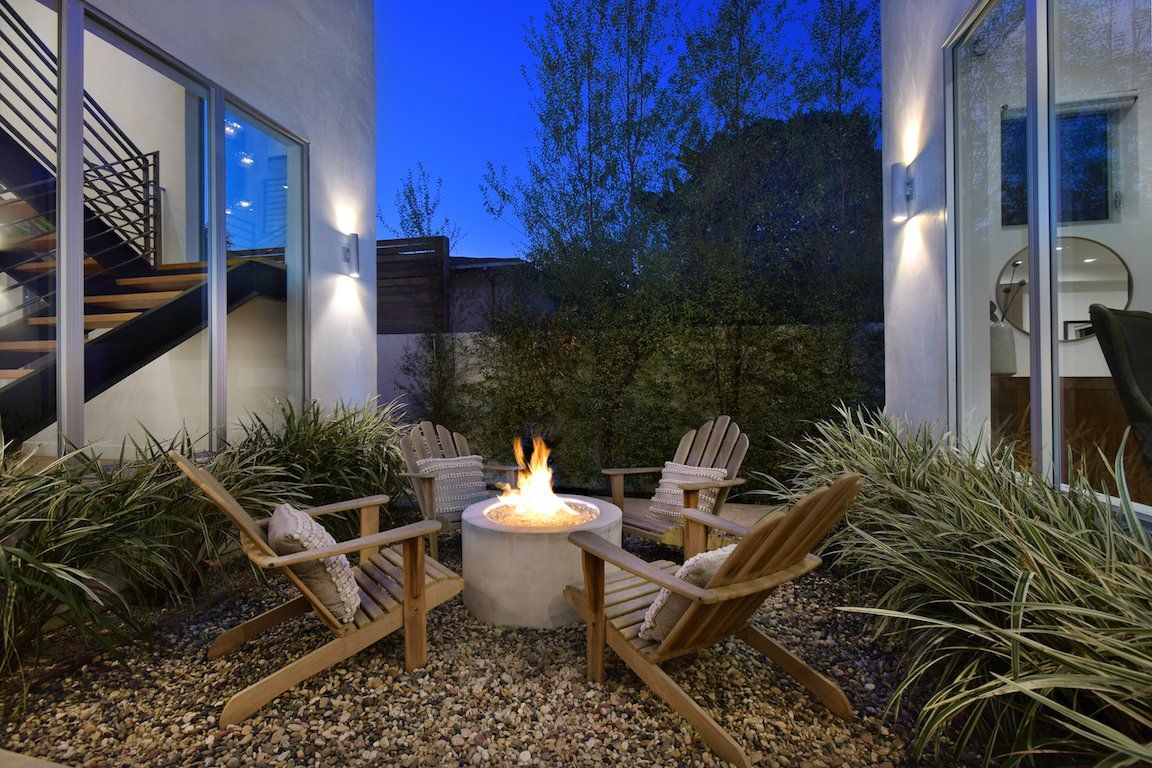 There is a fire pit in the middle of the patio surrounded by chairs.
