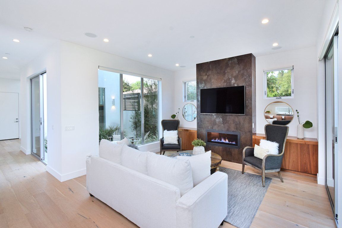 A living room with a couch , chairs , television and fireplace.