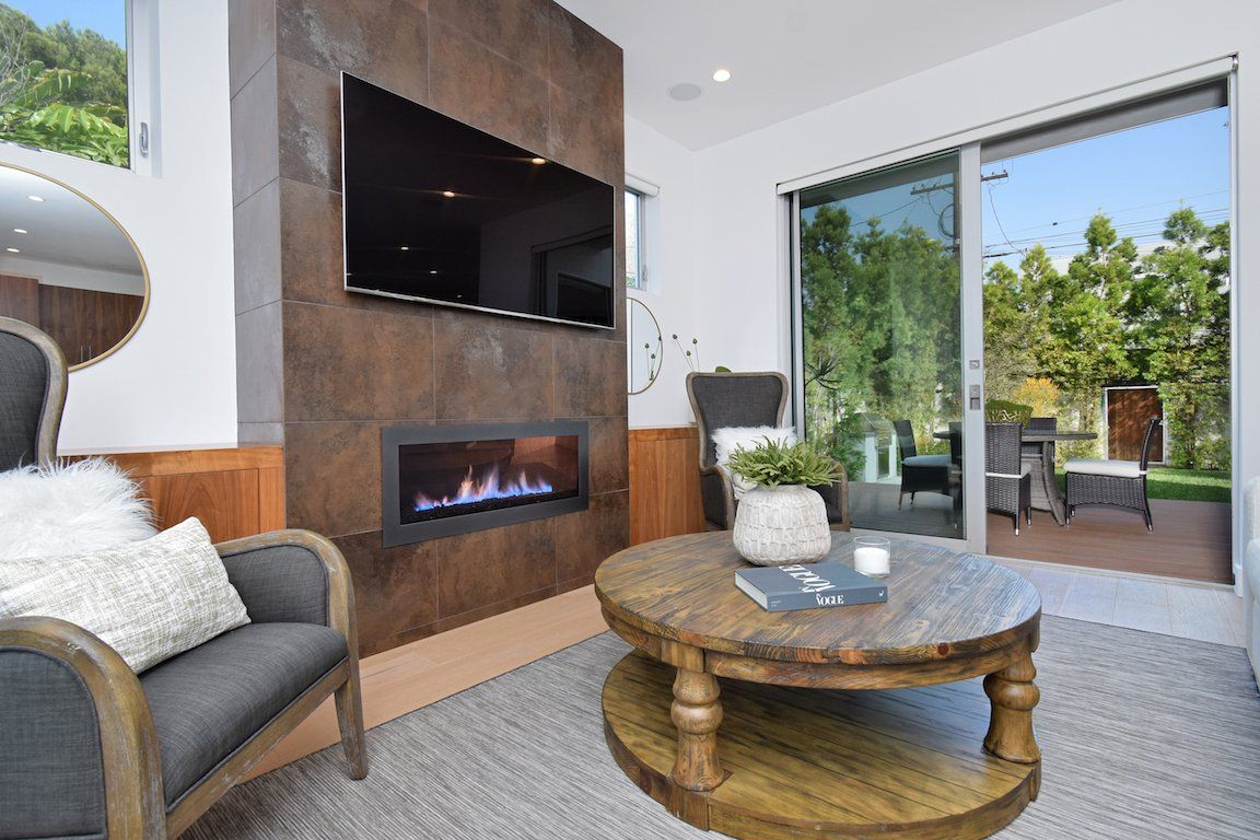 A living room with a fireplace , coffee table , chair and television.