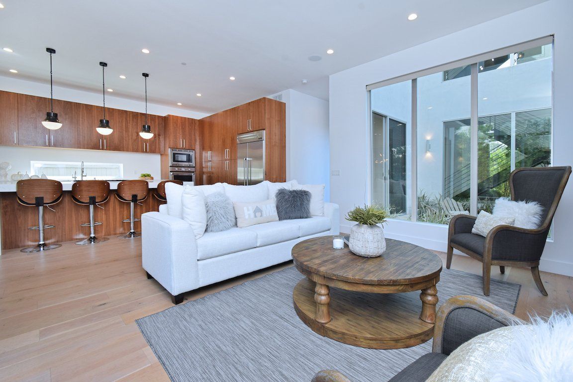 A living room with a couch , chair , coffee table and large windows.
