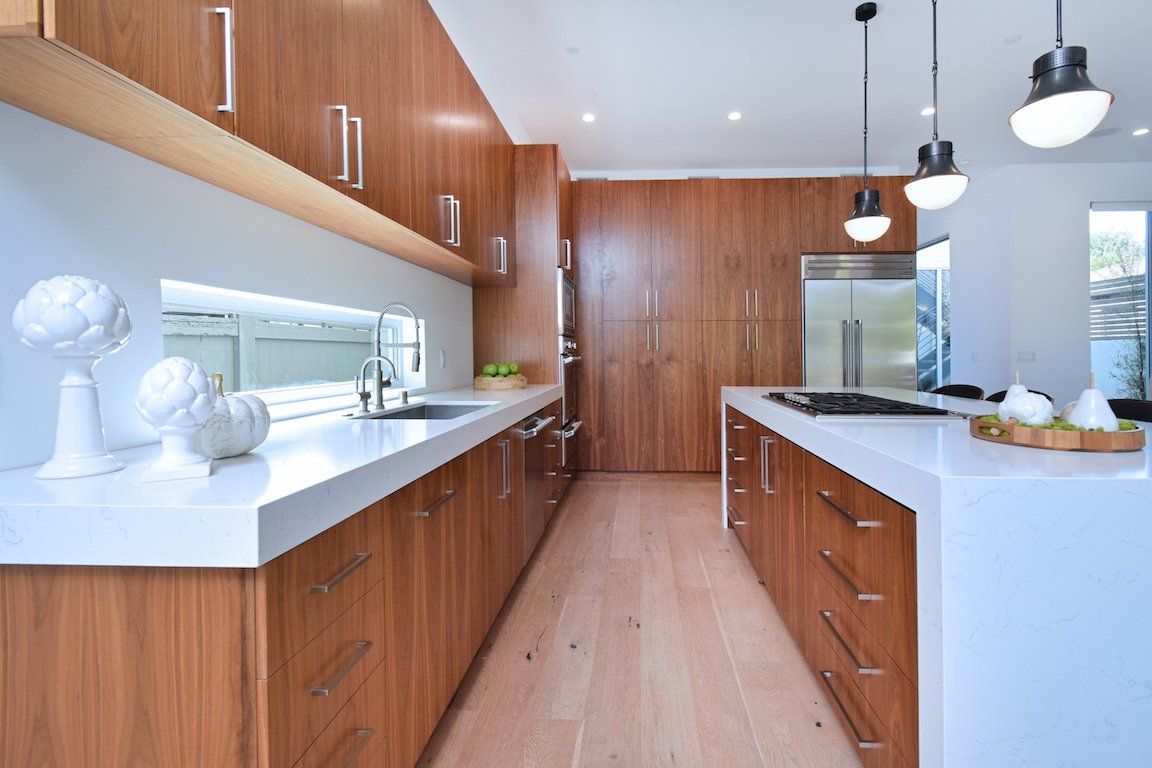 A kitchen with wooden cabinets and white counter tops