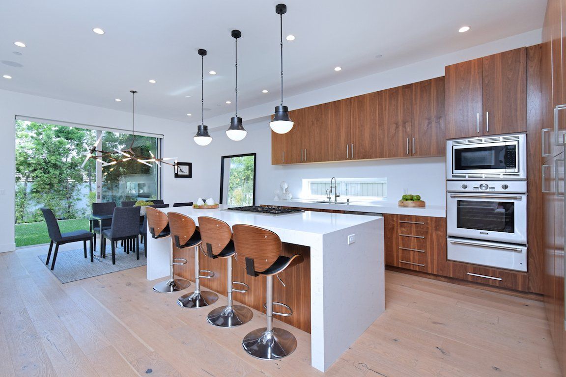 A kitchen with wooden cabinets and stools and a large island