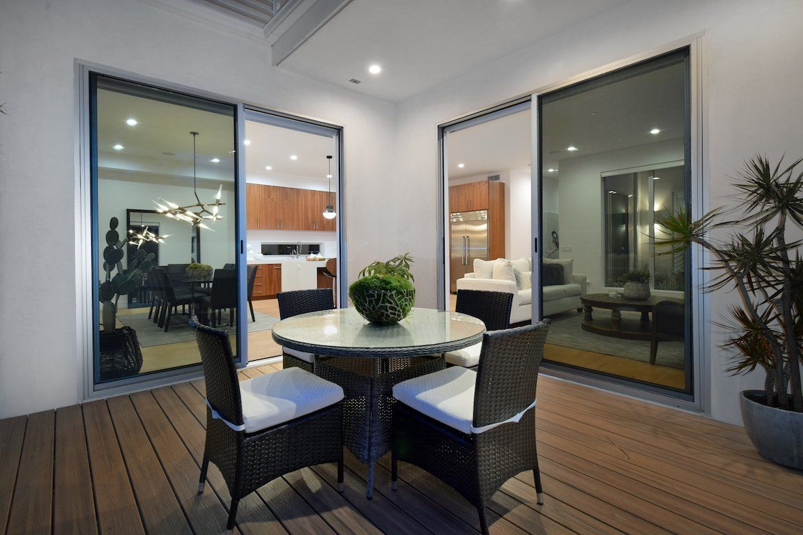 A patio with a table and chairs and sliding glass doors leading to a living room.
