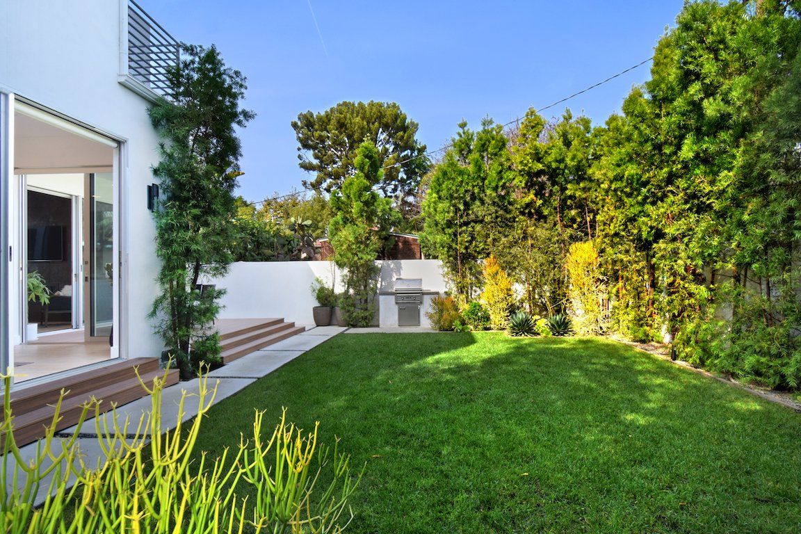 The backyard of a house with a large lawn and trees