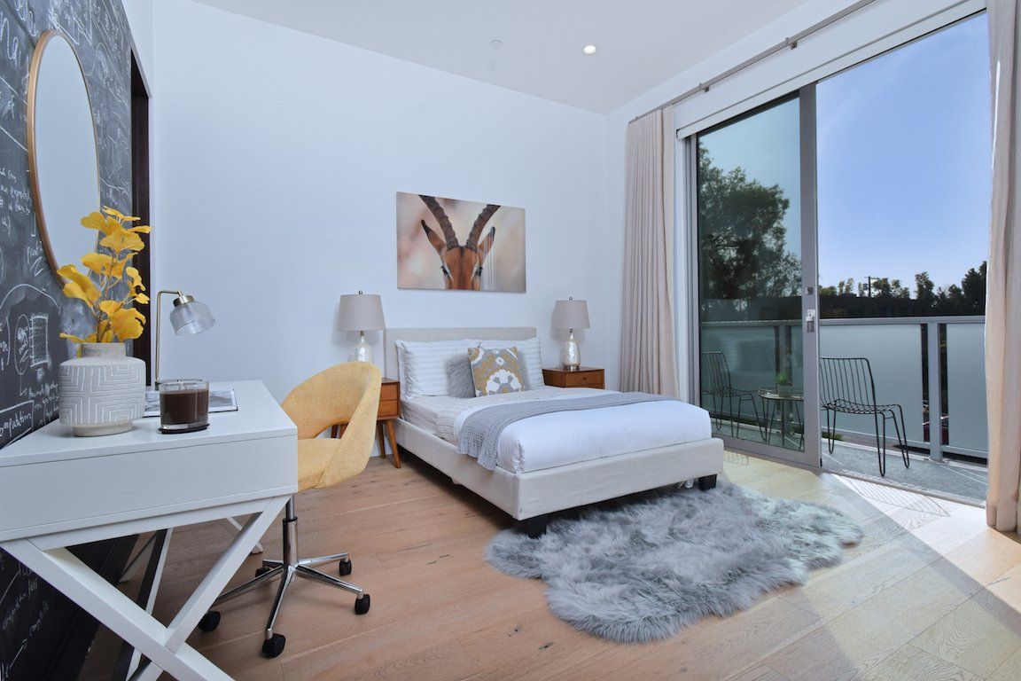 A bedroom with a bed , desk , chair and sliding glass doors.