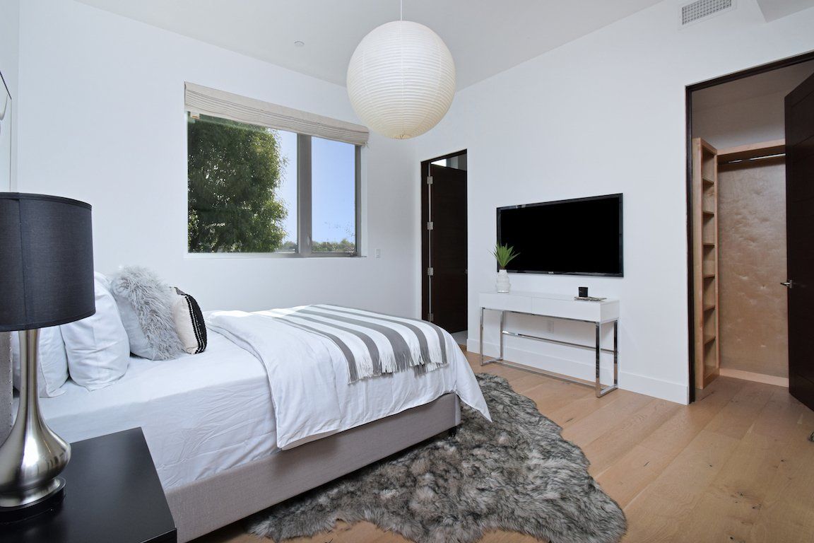 A bedroom with a bed and a television on the wall