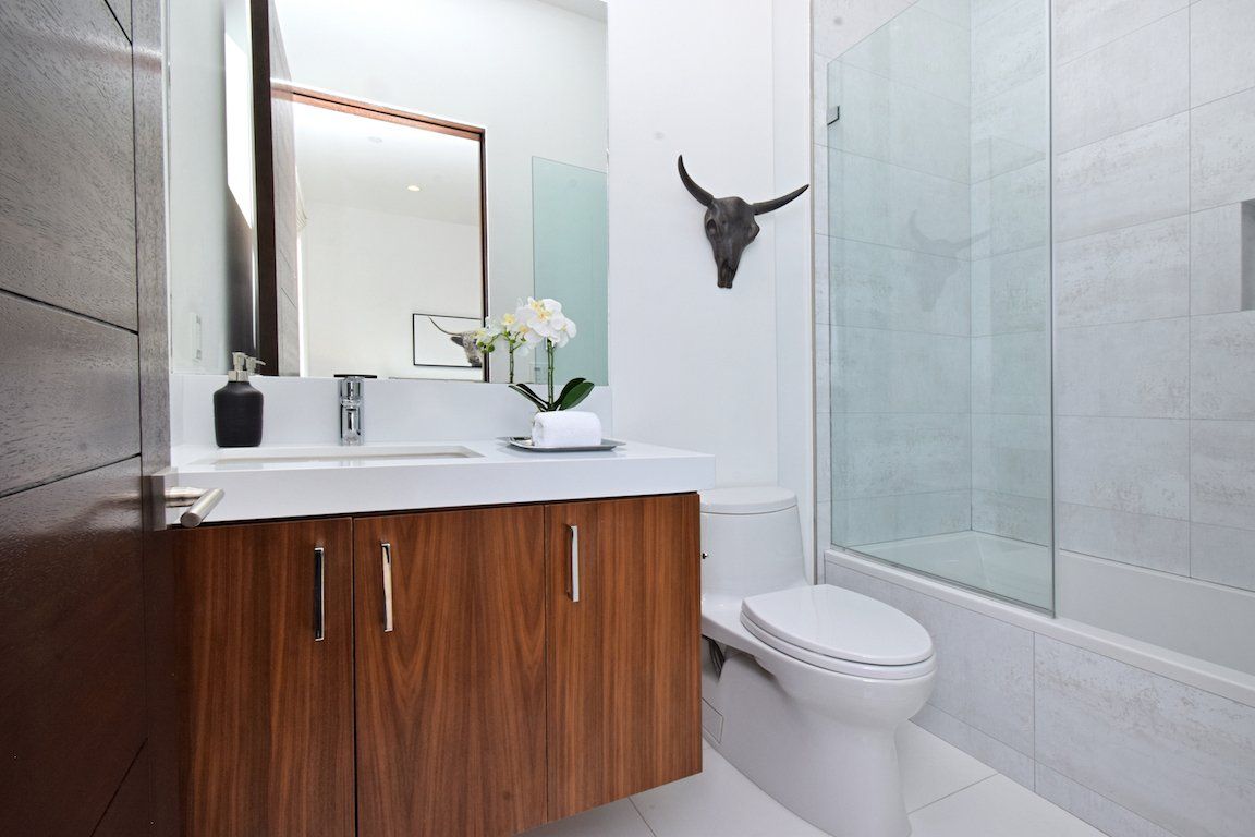 A bathroom with a toilet , sink , mirror and shower.