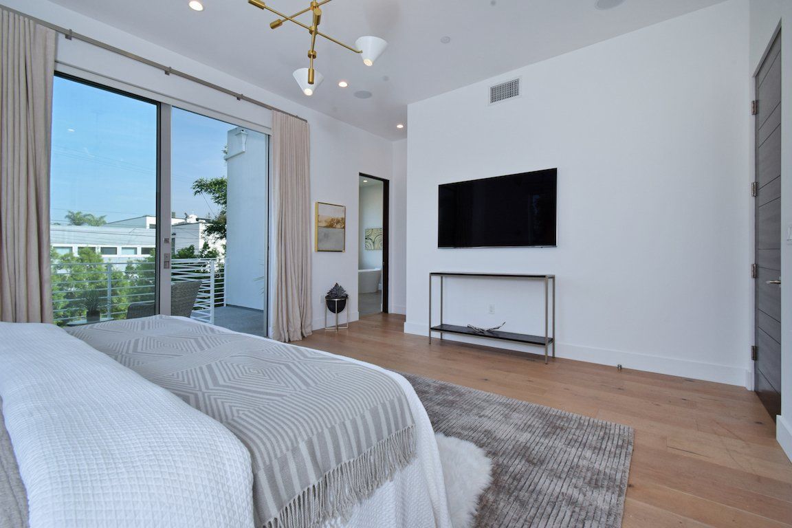 A bedroom with a large bed and a flat screen tv on the wall.