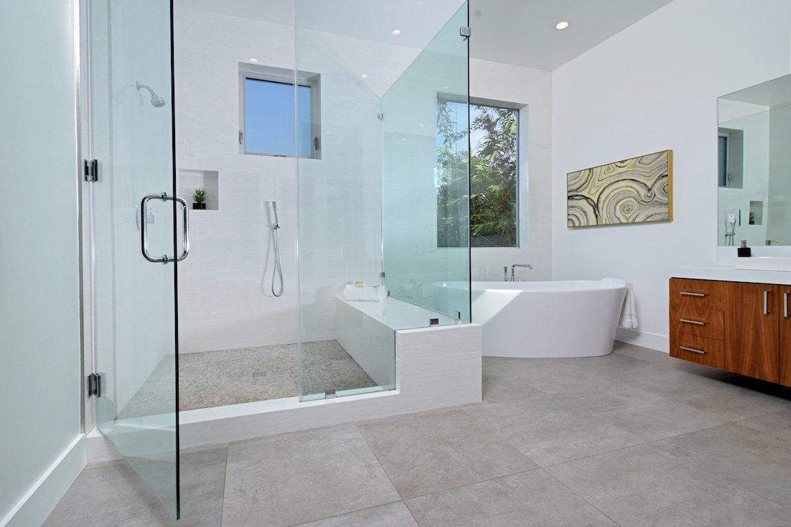A bathroom with a walk in shower , tub , sink and mirror.