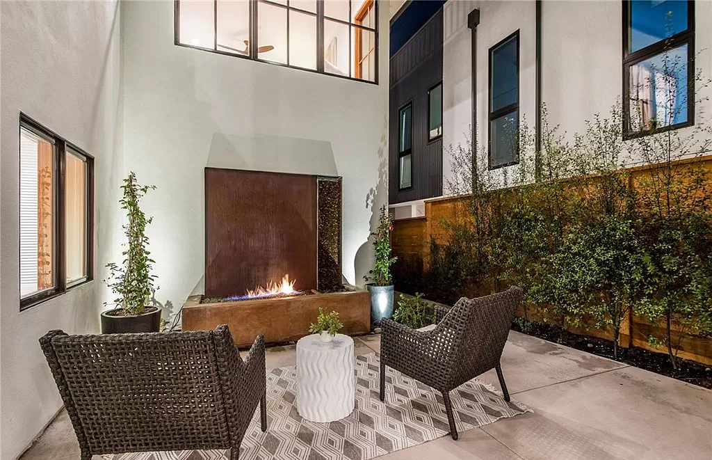 A patio with chairs , a table and a fireplace.