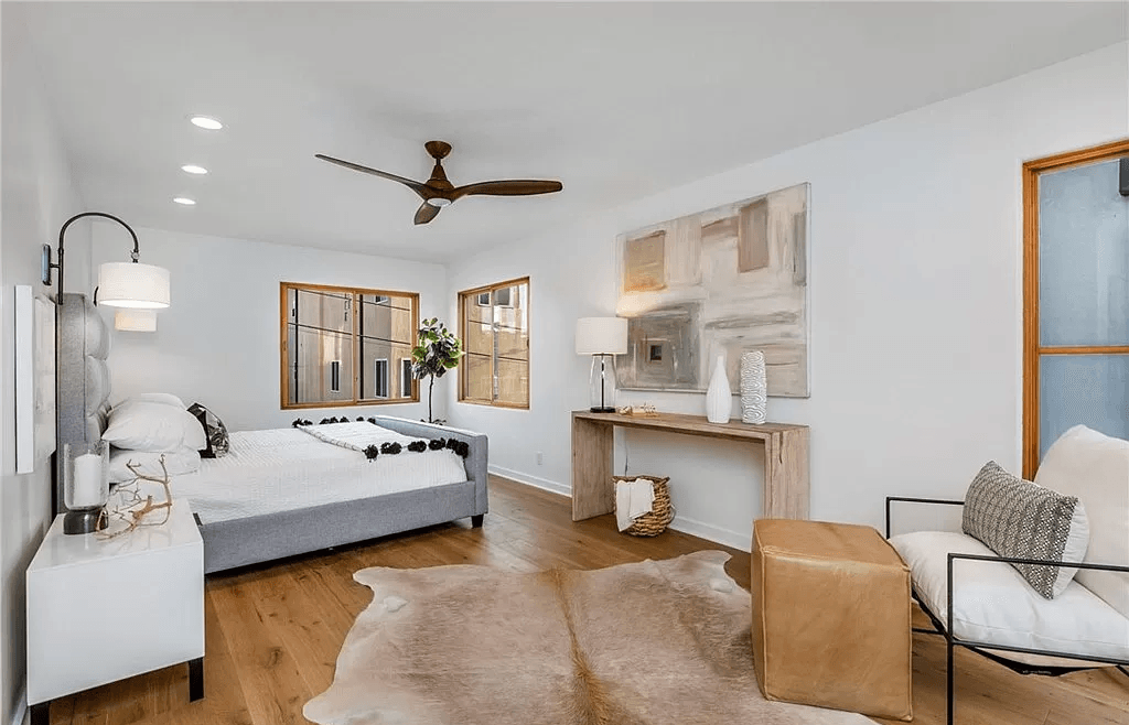 A bedroom with a couch , chair , rug and ceiling fan.