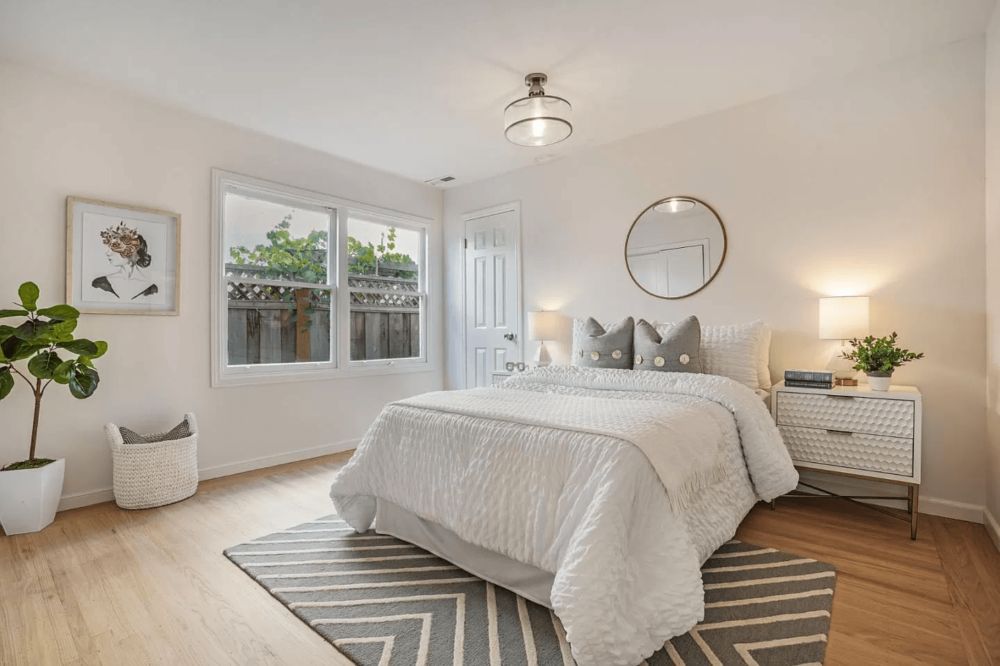 A bedroom with a bed , nightstand , mirror and rug.