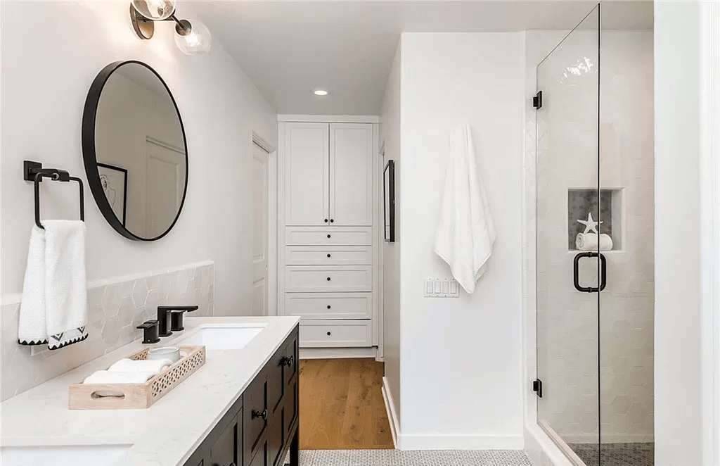 A bathroom with a sink , mirror , and walk in shower.