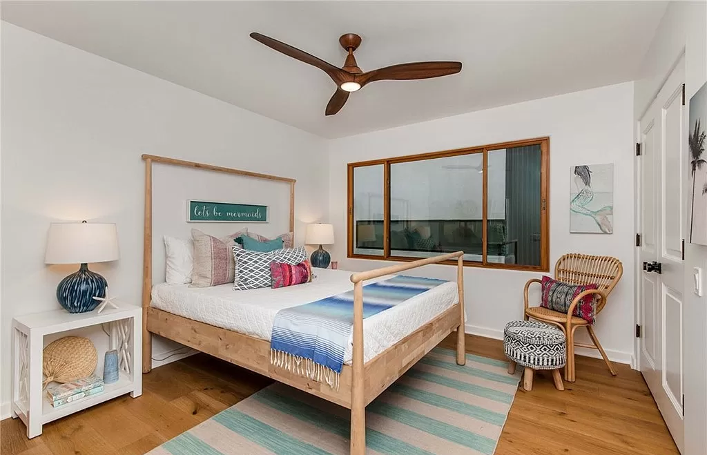 A bedroom with a bed , chair , nightstand and ceiling fan.