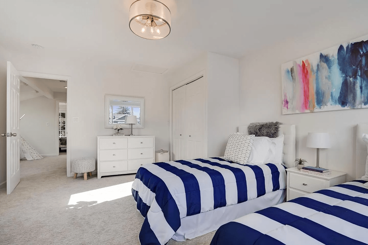 A bedroom with two beds , a dresser and a painting on the wall.