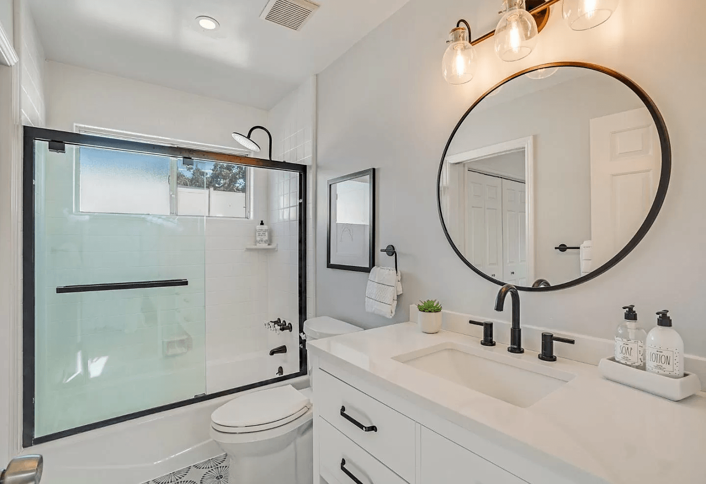 A bathroom with a toilet , sink , mirror and shower.
