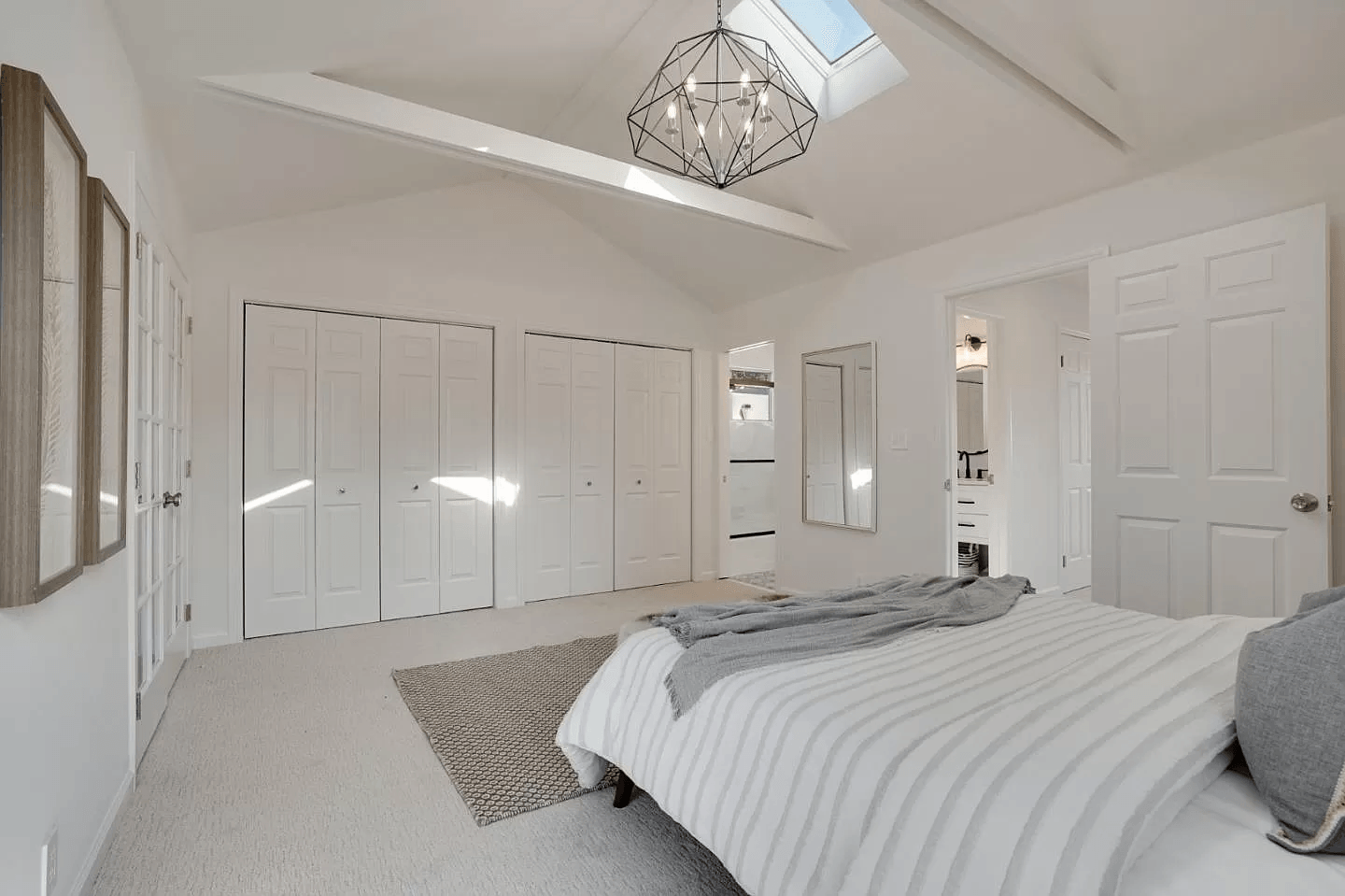 A bedroom with a bed , closets and a skylight.