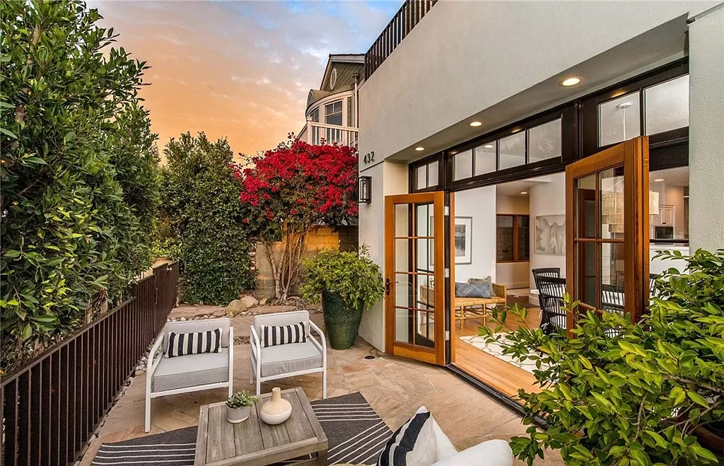 There is a patio with chairs and a table in front of a house.