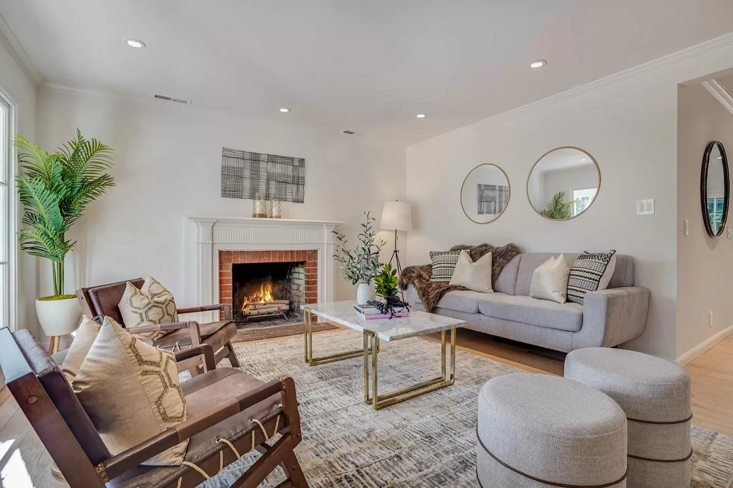 A living room with a couch , chairs , ottomans and a fireplace.