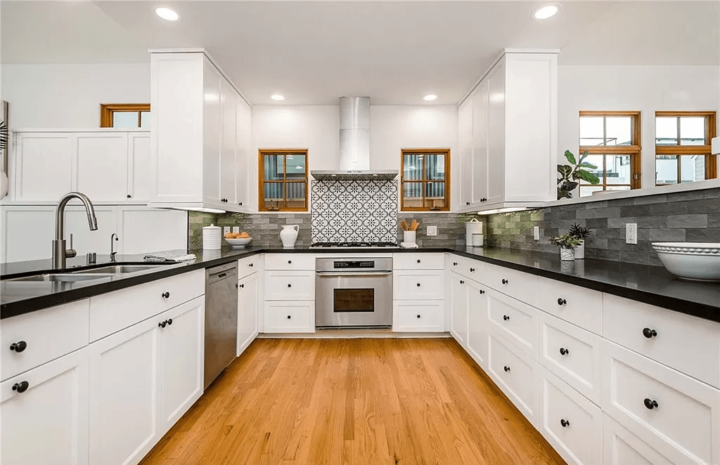 A kitchen with white cabinets , stainless steel appliances , and hardwood floors.