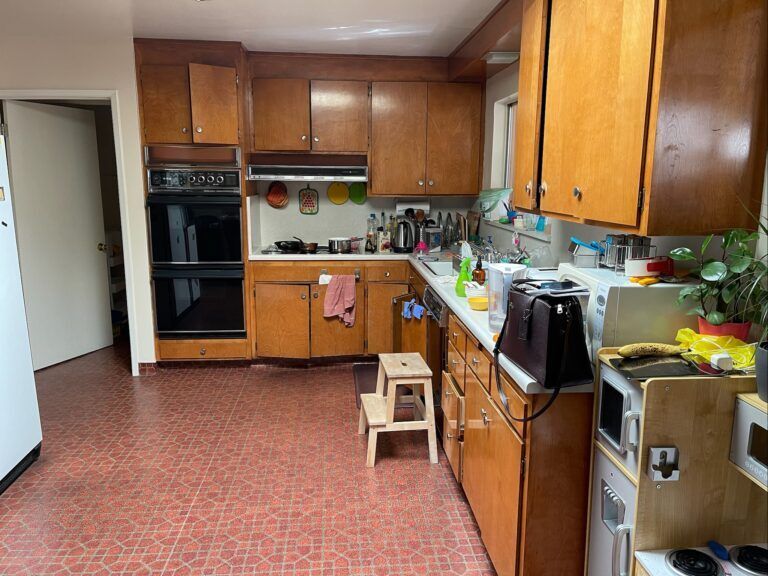 A kitchen with wooden cabinets and a red tile floor