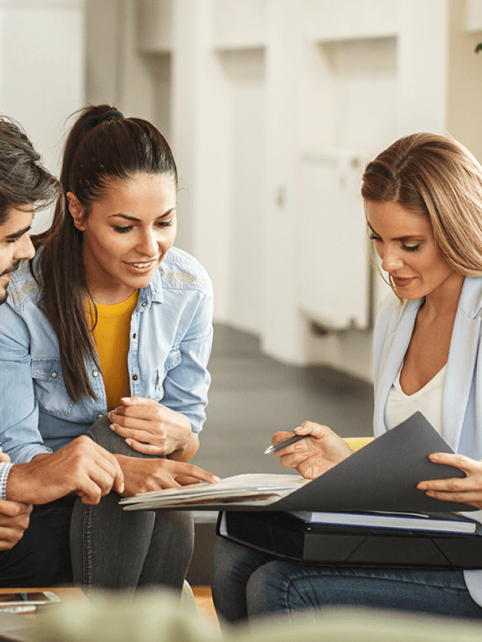 A group of people are sitting on the floor looking at a folder.