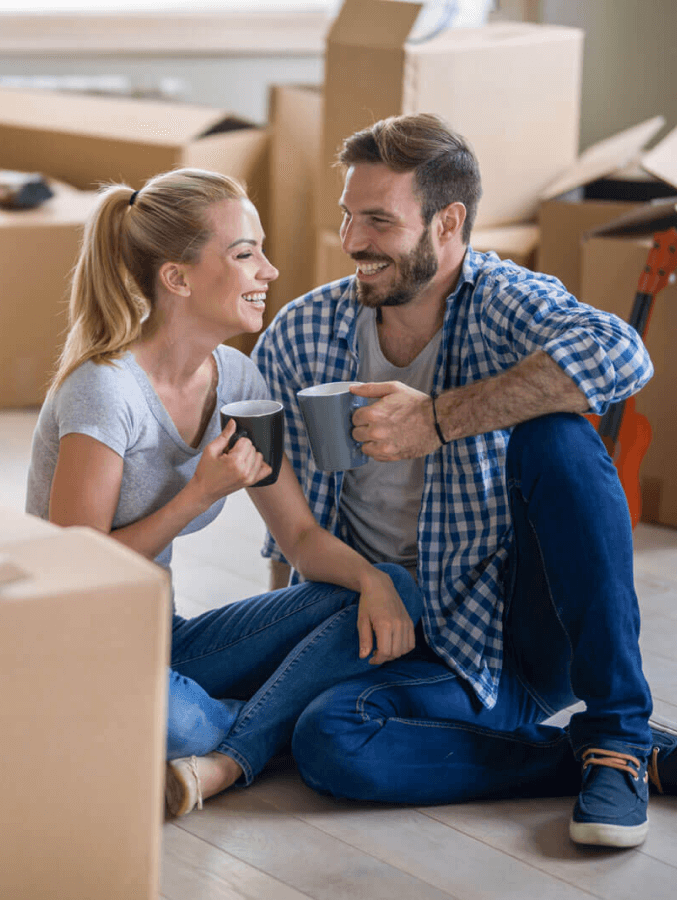 A man and a woman are sitting on the floor drinking coffee.