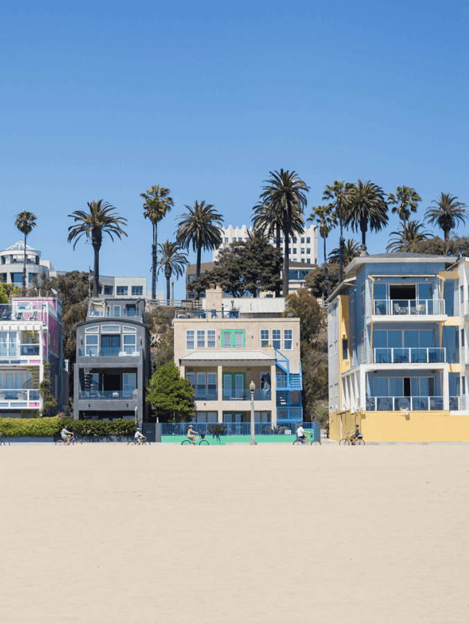 A row of houses on a beach with palm trees in the background